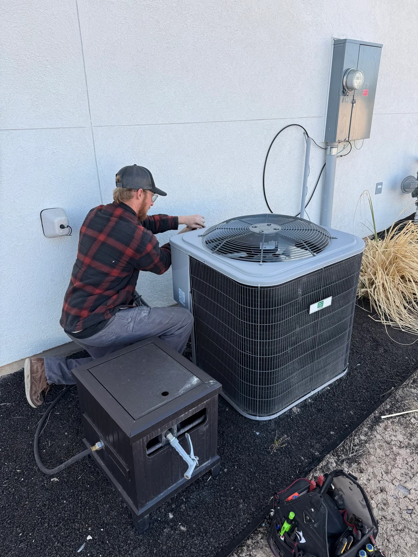 An All Around technician servicing an AC condenser at a Utah home