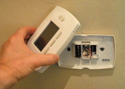 Home thermostat being checked after it stopped working properly.