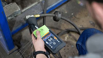 HVAC technician using an airflow meter to identify hidden air leaks around ductwork, helping prevent heat loss and improve winter home comfort.