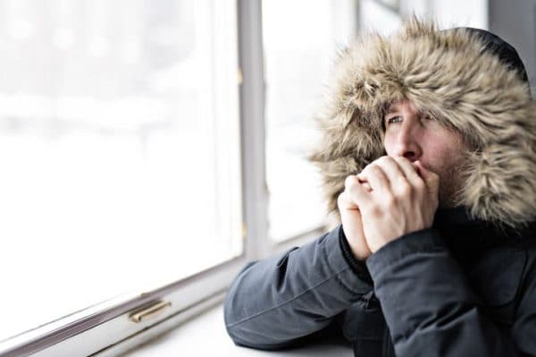 Person feeling cold indoors despite thermostat set to a warm temperature.