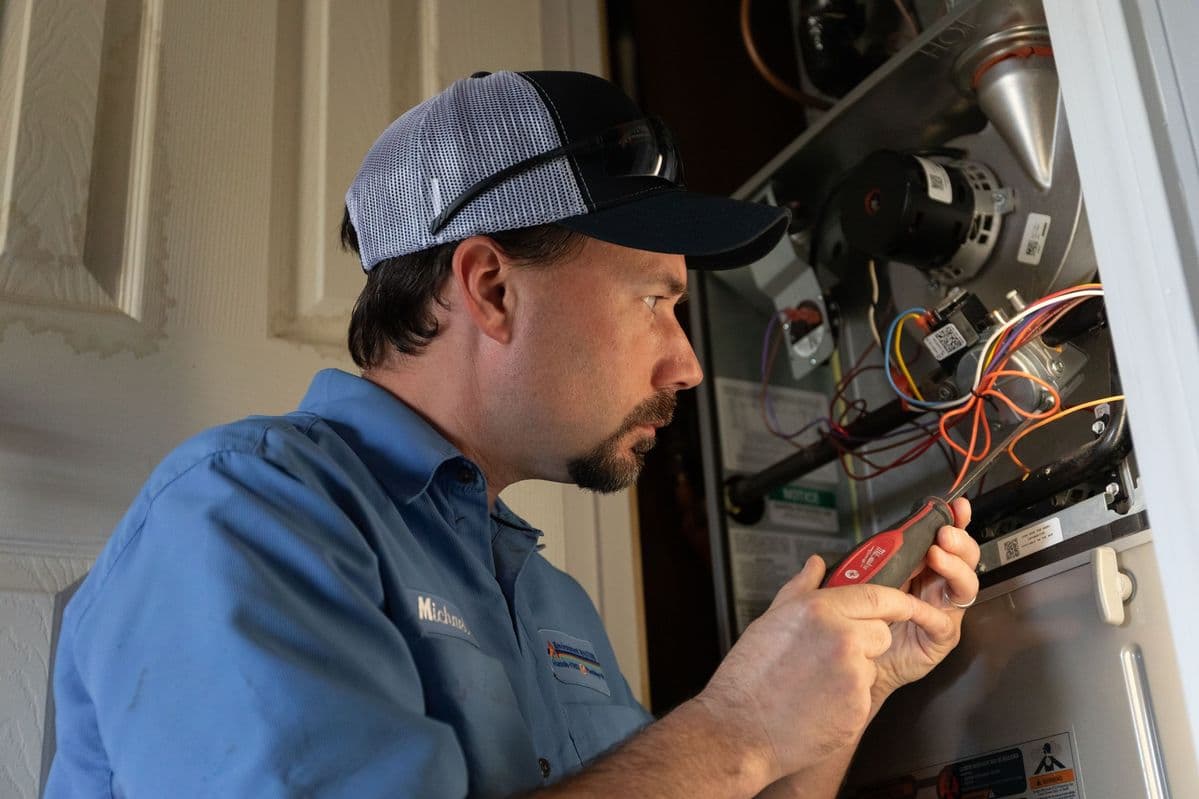 HVAC technician inspecting furnace wiring and components to diagnose airflow and efficiency issues.